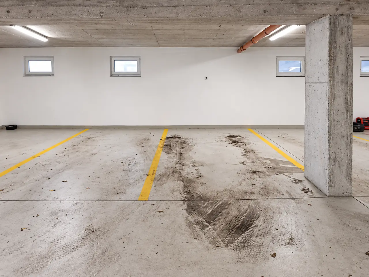 Társasházi mélygarázs tisztítás előtt – kerékkel behordott sár és szennyeződés a betonpadlón